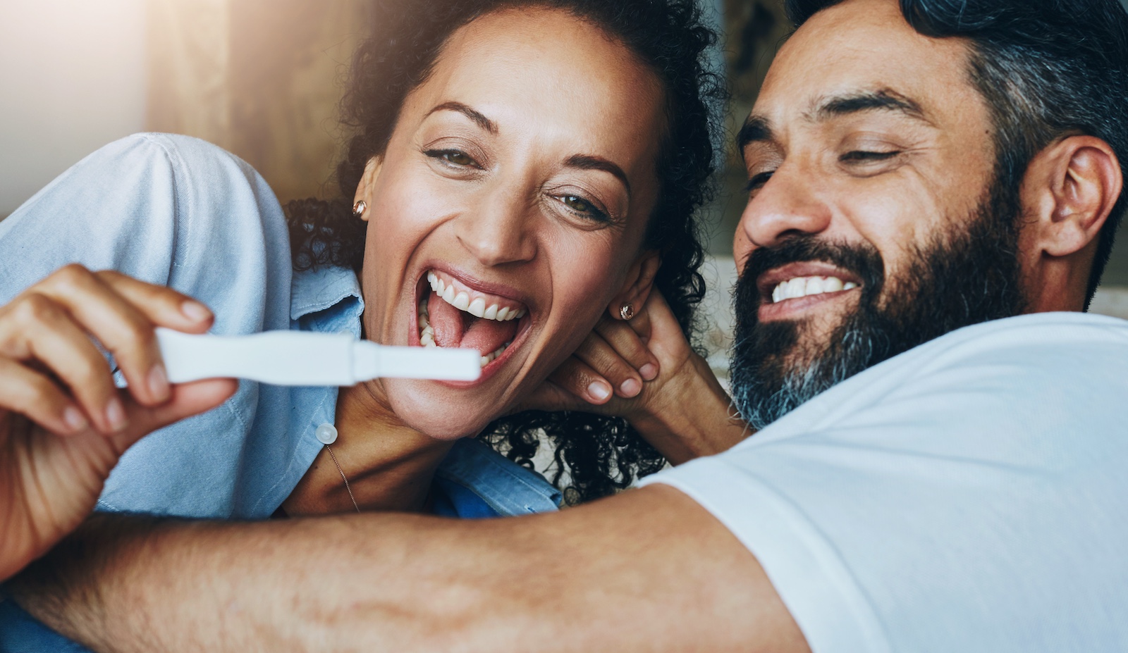 A married couple celebrates a positive pregnancy test result